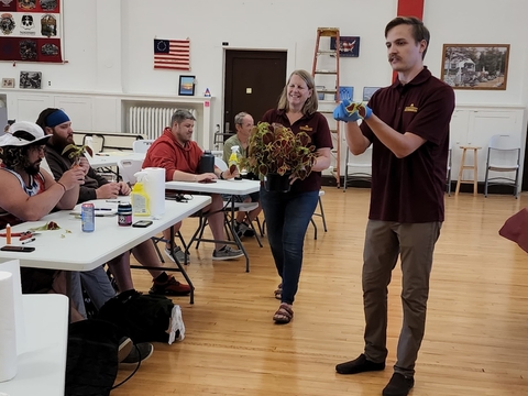 Noah and Julie teach veterans plant propogation in a room with an American flag