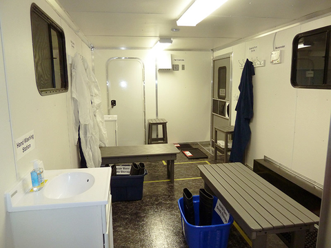 Interior of trailer with sink, benches, hooks for clothes, tubs on floor.