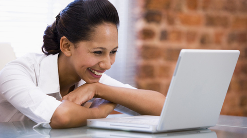 A businesswoman smiling while talking during an online meeting.