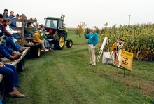 Mark Seeley giving a speech in front of a corn field to an audience on tractor
