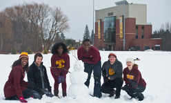 A group of youth in the snow on the University of Minnesota Duluth campus.