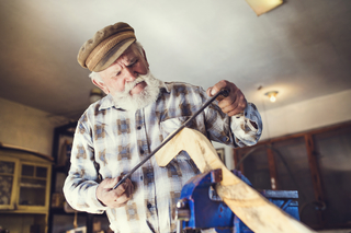 A senior woodworker working in their shop