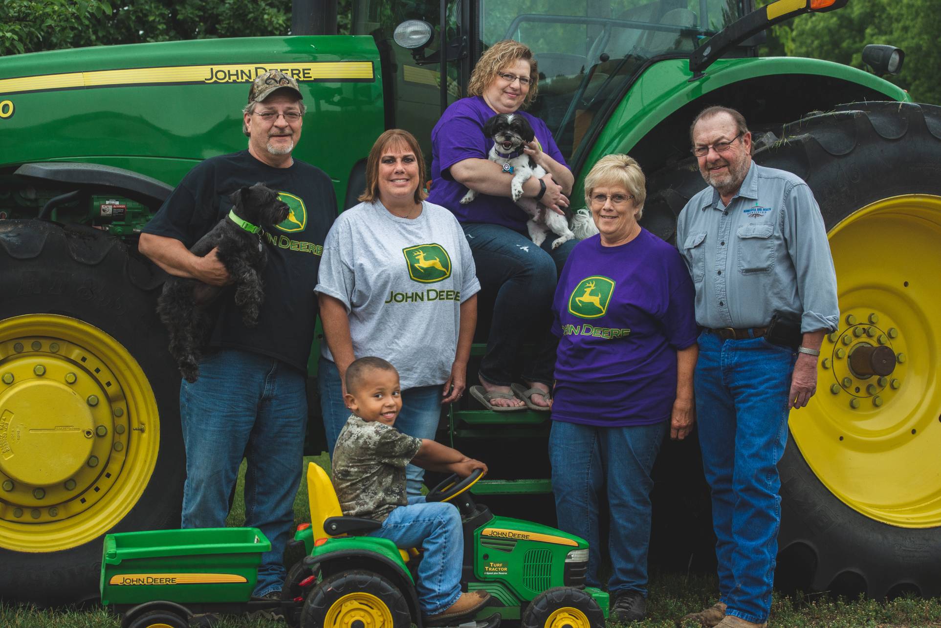 Ackerman family standing together in front of a John Deere tractor.