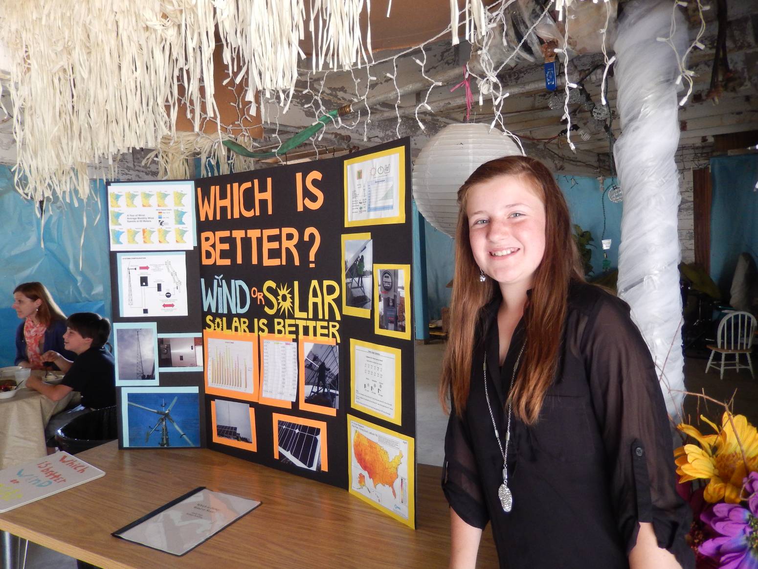 A student standing next to a table presentation about wind and solar.
