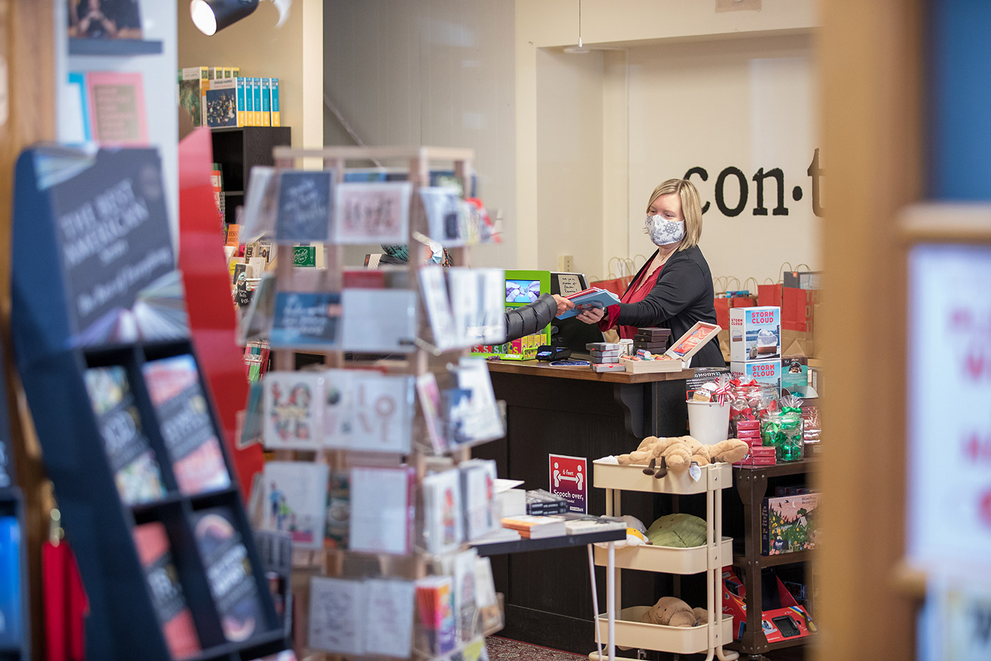 Store manager wearing a mask helping a customer purchase books