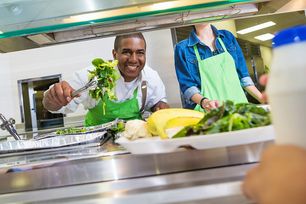 a cafeteria worker serving salad