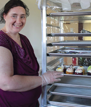 Woman standing by rack of cupcakes