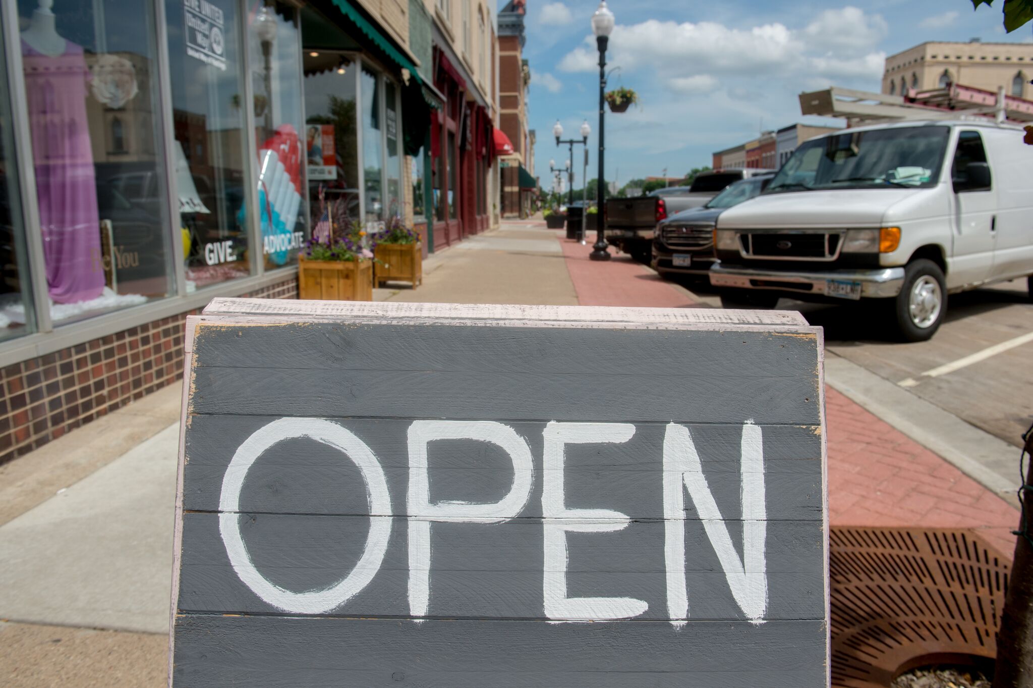 A downtown business open sign displayed on the sidewalk.
