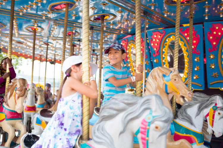 Young kids at a festival enjoying a ride on a merry-go-round horses