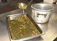 Ladeling soup into shallow pan.