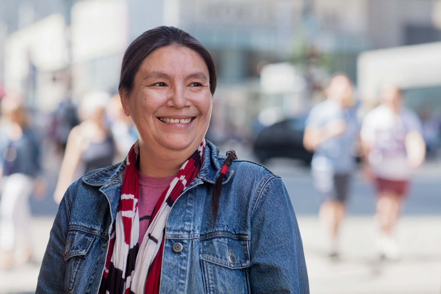 A Native American person smiling while standing in an urban area