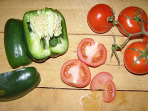 Green peppers and red tomatoes on brown table cut open to show their seeds