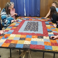 Eight quilters work on a colorful quilt