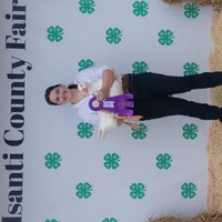 Ella L. posing for photo with duck and grand champion ribbon