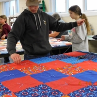 Teen and adult work on red and blue quilt
