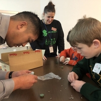 A man helping a young boy with a science activity. 