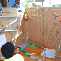 A young person looks at a Rube Goldberg Machine that has tracks and a mannequin.