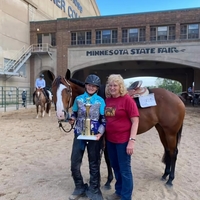 Alison M. posing with trophy, horse, and volunteer