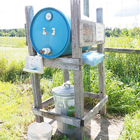 Handwashing stand built of lumber with large plastic drum to dispense water