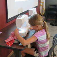 4-H youth working on project with sewing machine at 4-H camp