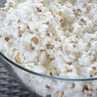A close up of a glass bowl holding popcorn.