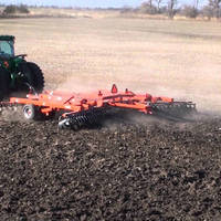 A green tractor pulling tillage equipment in a field that has already been harvested.