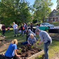 A group of community members help plant a raised garden bed