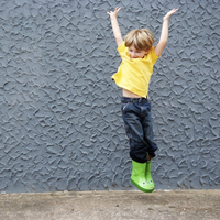 Young boy jumping in the air with both hands raised