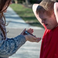 A woman showing a man with Down syndrome a phone.
