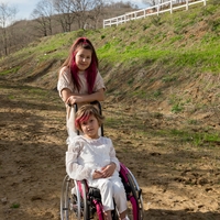 A girl standing behind a girl in a wheelchair