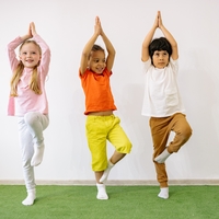 three youth in a line standing on one foot doing a yoga pose