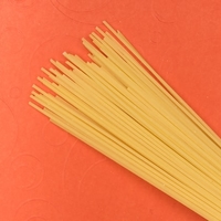 Spaghetti noodles on orange background