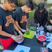 Three youth working on food prep outdoors