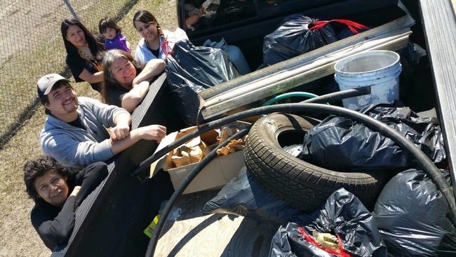 Group of people standing around a trailer full of garbage collected on earth day clean up