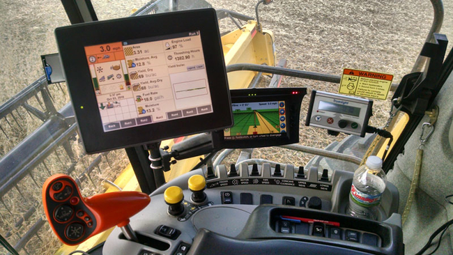 inside a modern tractor cab - several computer screens, monitors and control levers.