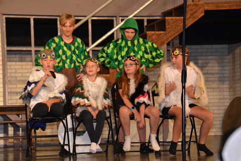 A group of youth wearing costumes on a stage.