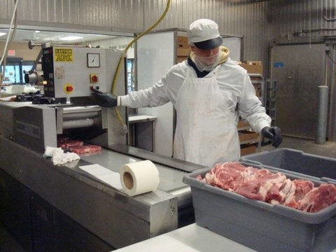 Man standing behind commercial meat cutting system.