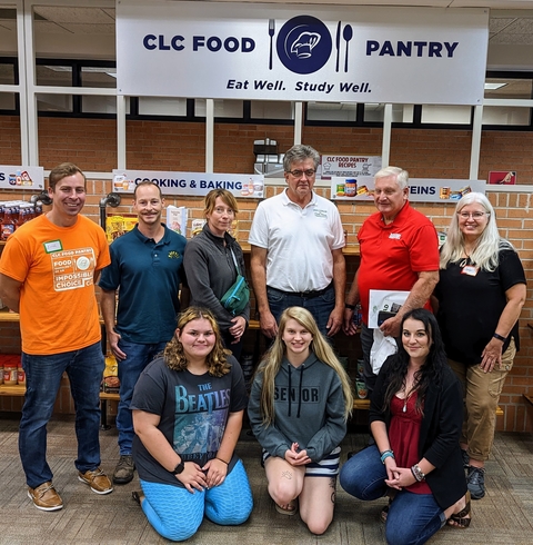 Nine people pose in front of the CLC Food Pantry