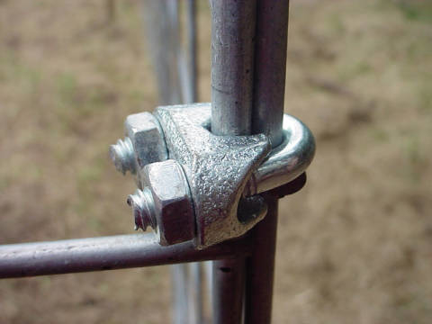 A metal clamp with two bolts fit around a metal post.