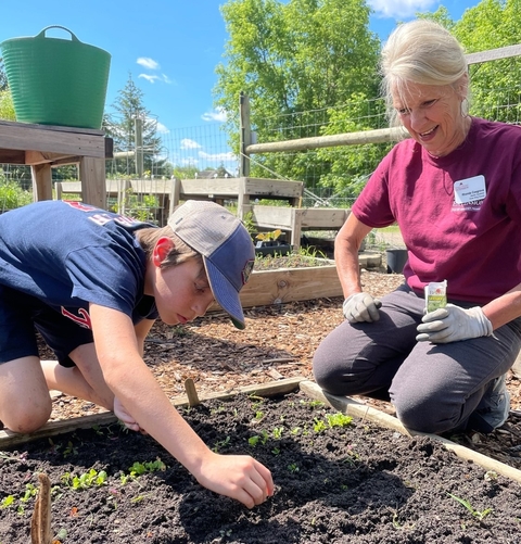 A Crow Wing County Master Gardener volunteer working with a youth in a garden. 