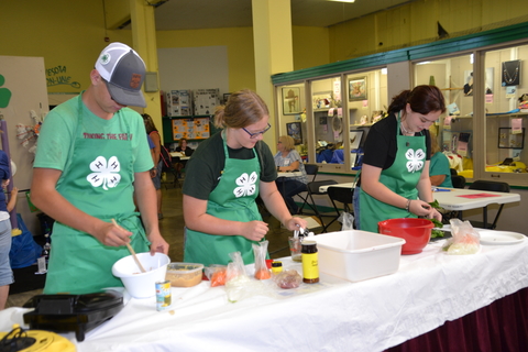 Youth wearing 4-H aprons cooking