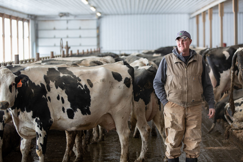 Dairy farmer standing in front of many black and white cows