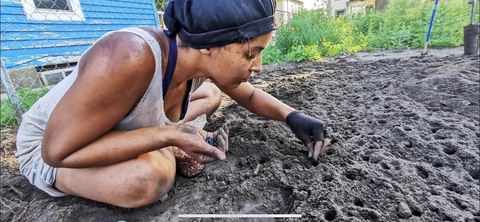 Dennika Mays sits in the dirt planting a garden for a mutual aid group in Minneapolis. 