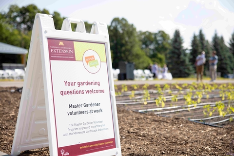 A sign on the ground reads "Your gardening questions answered and has the University of Minnesota Extension logo. Other text is small and not readable.