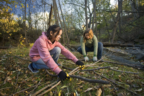 Two girls cleaning up a woodland area