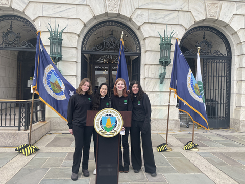 Four girls standing behind a podium with the United States Department of Agriculture emblem on it.