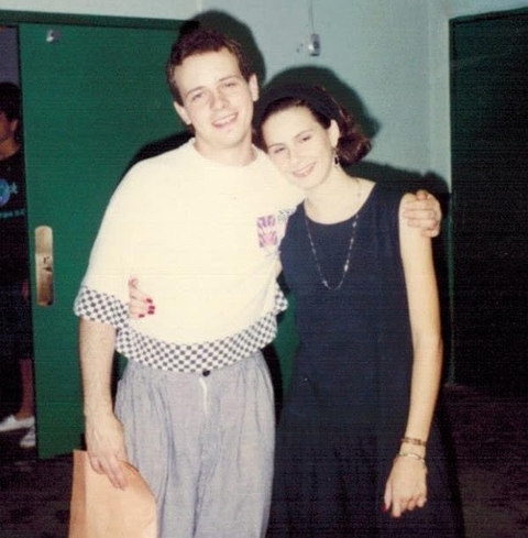 Vintage snapshot of two teen youth embracing with a green inside door of the 4-H building behind them