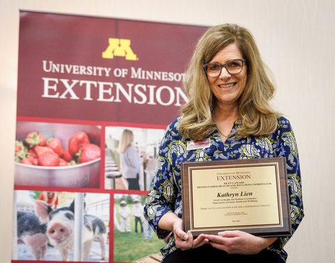 Award winner holding plaque in front of Extension banner
