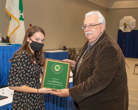 4-H youth receives award plaque from judge