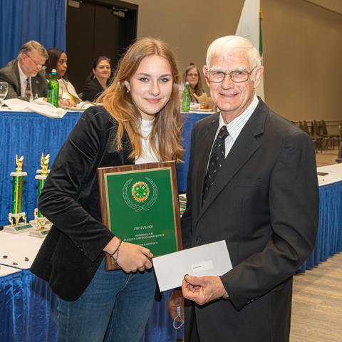 4-H youth holds award plaque presented by judge.